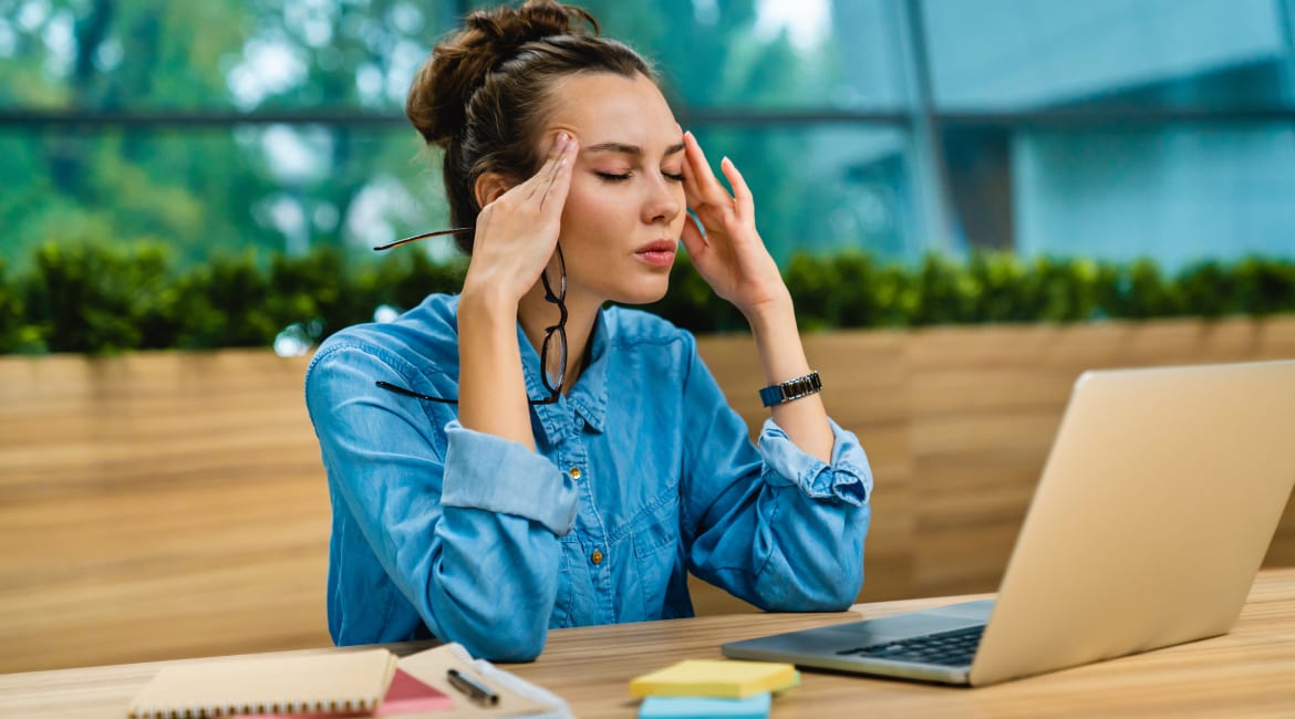 Tired caucasian 20s busy girl trying to concentrate sitting against laptop in spacious office