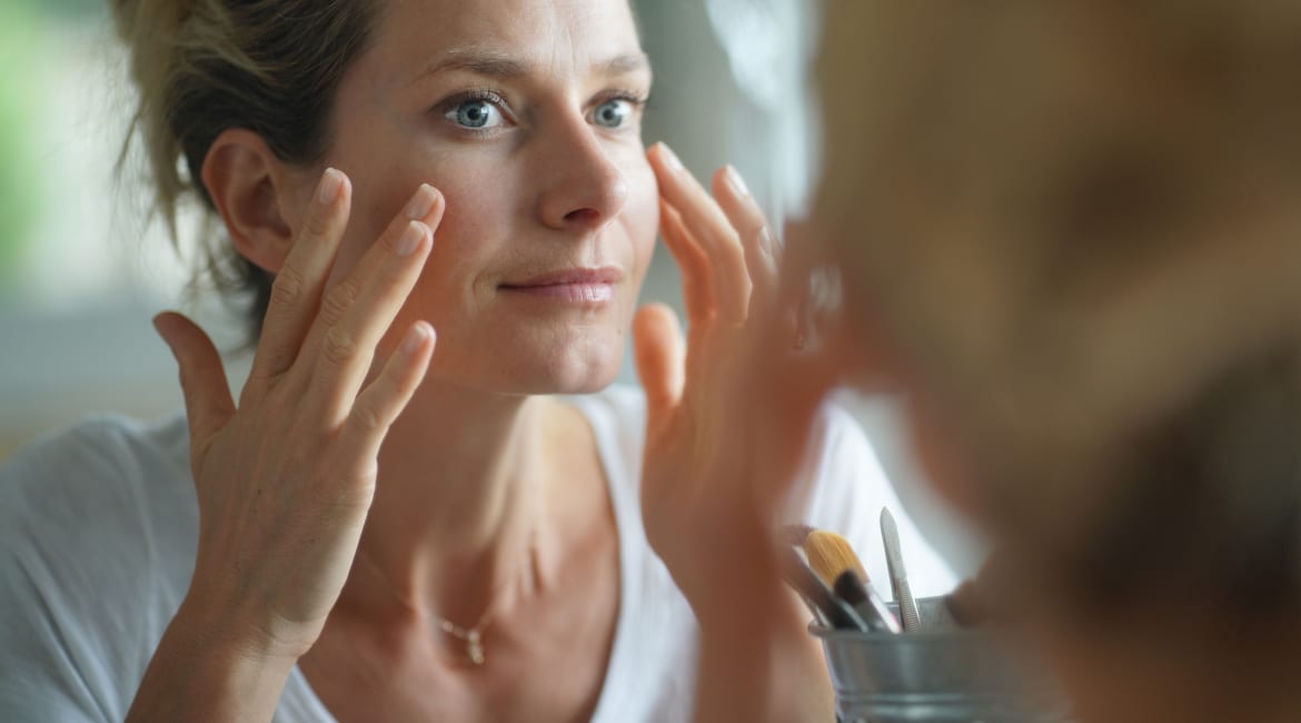 Portrait of woman looking at her face in mirror