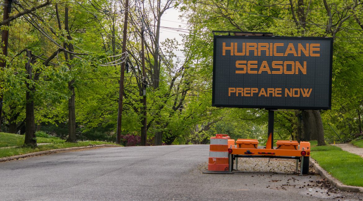Digital electronic mobile road sign that says Hurricane Season prepare now, on the side of a tree lined road
