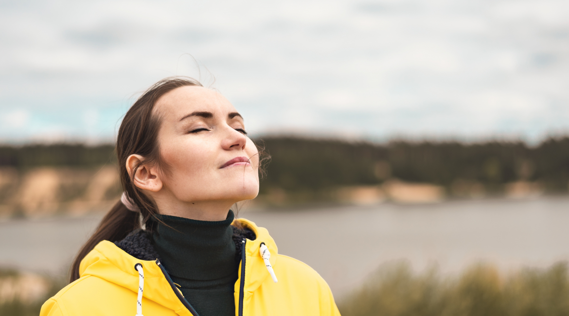 Portrait of a young woman in nature in a yellow jacket breathing fresh clean cool autumn air with a copy space