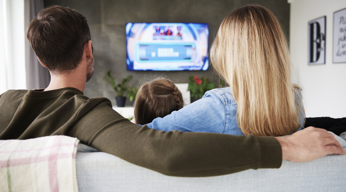 Rear view of family watching tv in living room