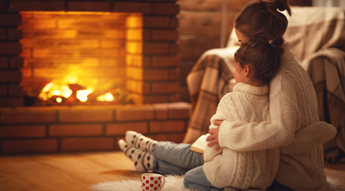 family mother and child hugs and warm on winter evening by fireplace
